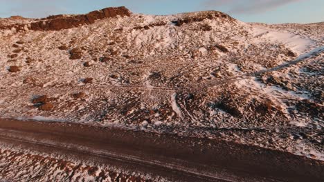 Beautiful-Icelandic-Eroded-Mountain-Partly-Covered-In-White-Snow-With-Blue-Sky-Above--racer-drone-shot