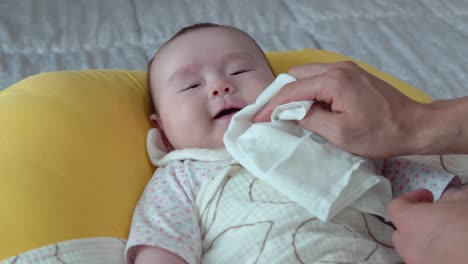 hands wiping baby's lips with a soft cloth - high angle shot