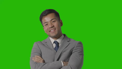 portrait of businessman in suit against green screen smiling at camera