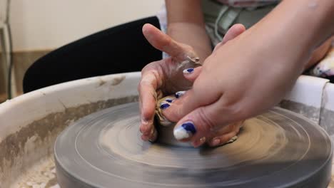 young woman artist making clay bowl on pottery wheel