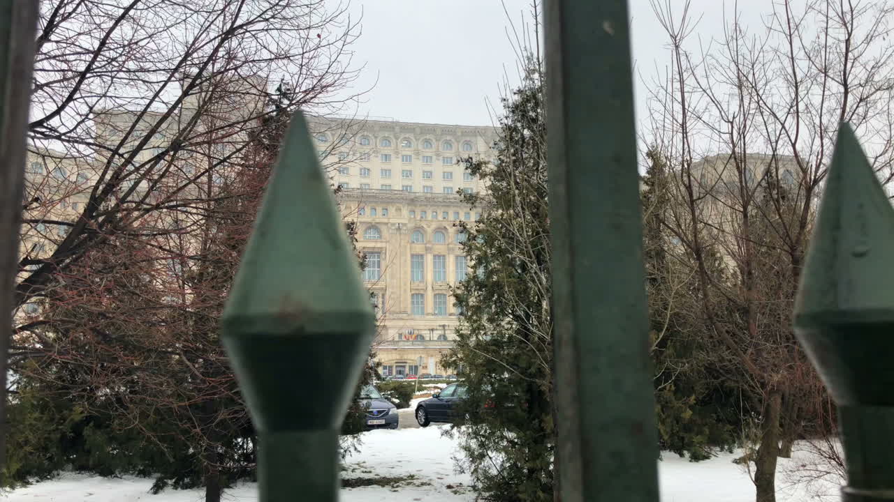 palacio del parlamento a través de una valla de metal en invierno