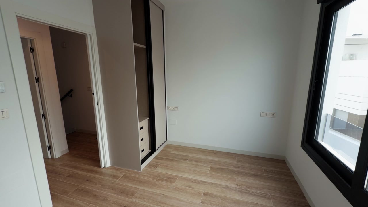 Empty interior of a newly built apartment room with wooden flooring and built-in wardrobe. Clean walls, natural light and minimal design make it suitable for real estate, rental or property listings.