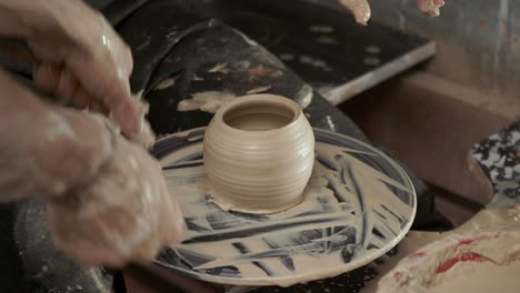 a potter teaches a woman to make clay dishes. a man takes a woman's hands