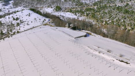 aerial view of a snow-covered mountain landscape with a house and a field of stakes