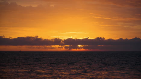 Majestic-Orange-Golden-Colorful-Sunset-Over-Sea-and-Bright-Sun-Light-Reflecting-in-Low-Clouds