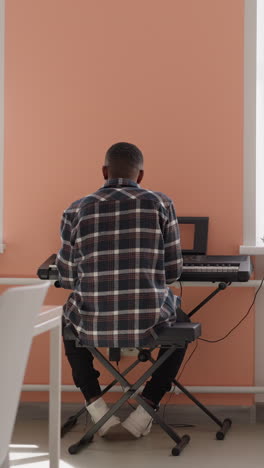 hombre negro se involucra con sintetizador. artista afroamericano ensaya melodía en instrumento eléctrico en la academia de música. preparación para la actuación