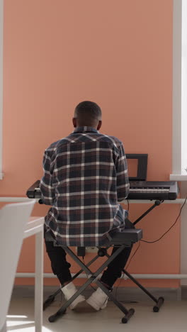 black man engages with synthesizer. african american artist rehearses melody on electric instrument in music academy. preparation for performance