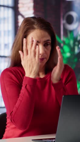 Vertical Video Exhausted woman trying to solve daily tasks on laptop at home office