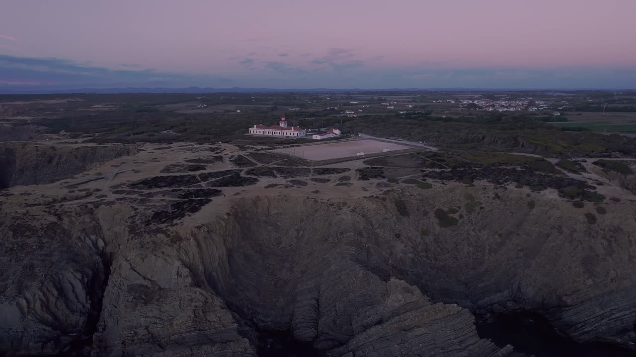 Historisk fyrtårn Farol do Cabo Sardão med udsigt over stratificerede atlantiske klipper inden for Parque Natural do Sudoeste Alentejano e Costa Vicentina, etableringsoptagelse med drone.