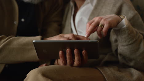 las manos de una pareja de ancianos usando una computadora tablet en primer plano. vieja familia chateando en línea
