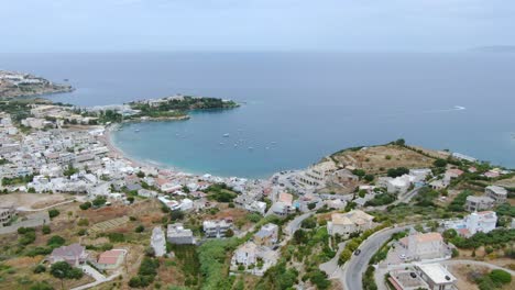 Vista-Aérea-Idílica-Ciudad-De-Playa-Y-Bahía-De-Mar-Turquesa,-Isla-De-Creta