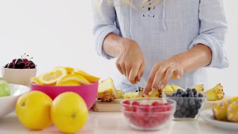 Woman-cutting-pineapple-on-chopping-board