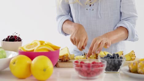 mujer cortando piña en la tabla de cortar