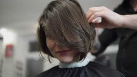 Professioneller-Friseur,-Stylist,-Der-Die-Haare-Einer-Kundin-Kämmt-Und-Eine-Haarspange-Zum-Fixieren-Der-Frisur-Im-Professionellen-Friseursalon-Verwendet.-Schönheits--Und-Haarpflegekonzept