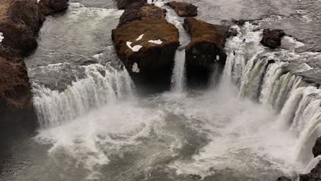 aerial view of goðafoss waterfall in iceland, snow-covered rocks and water flow.