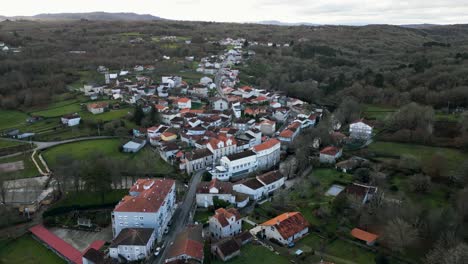 drone dolly descends above white buildings on river molgas in quaint village in spanish countryside