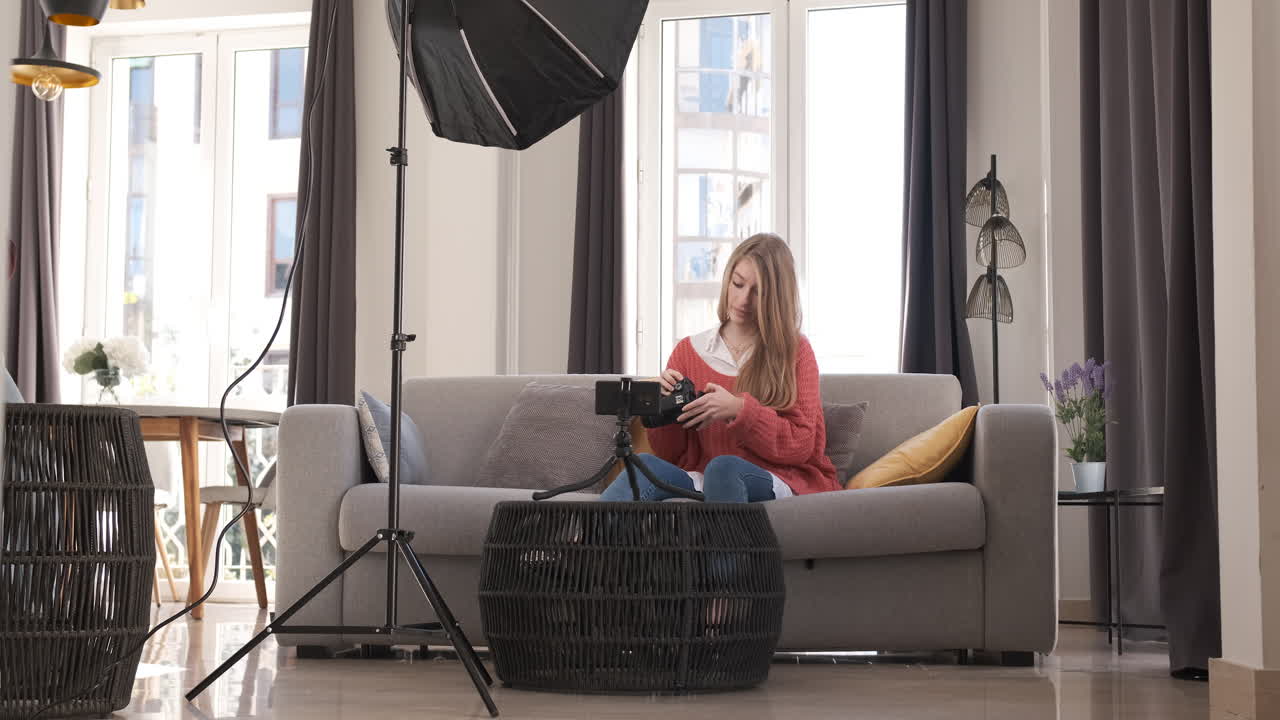 Young woman talking on mobile camera, explaining a photo camera. Content creator concept