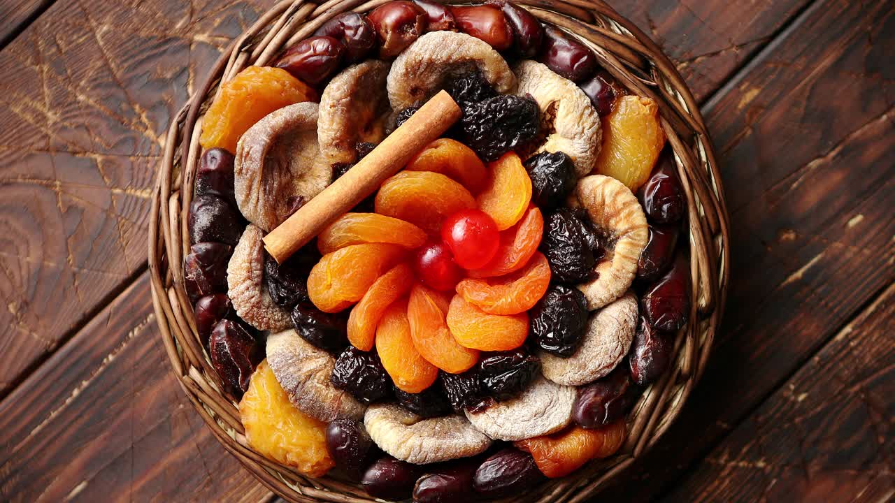 Mix of dried fruits in a small wicker basket on wooden table