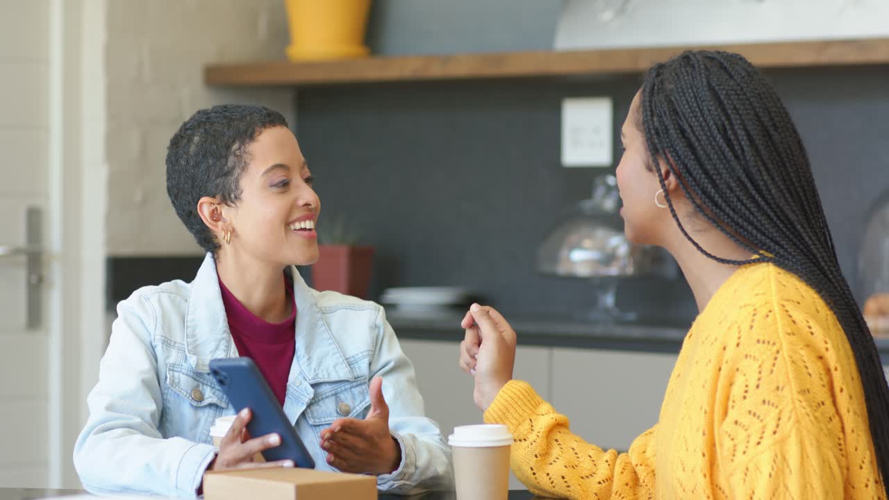 Mulheres afro-americanas amigas gesticulando e usando um tablet para compartilhar conteúdo em um café