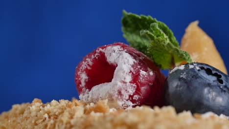 close-up of a cake with raspberries, blueberries, and mint