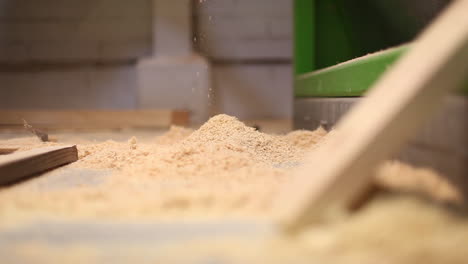 close up view of sawdust falling, creating a pile on the floor in the workshop