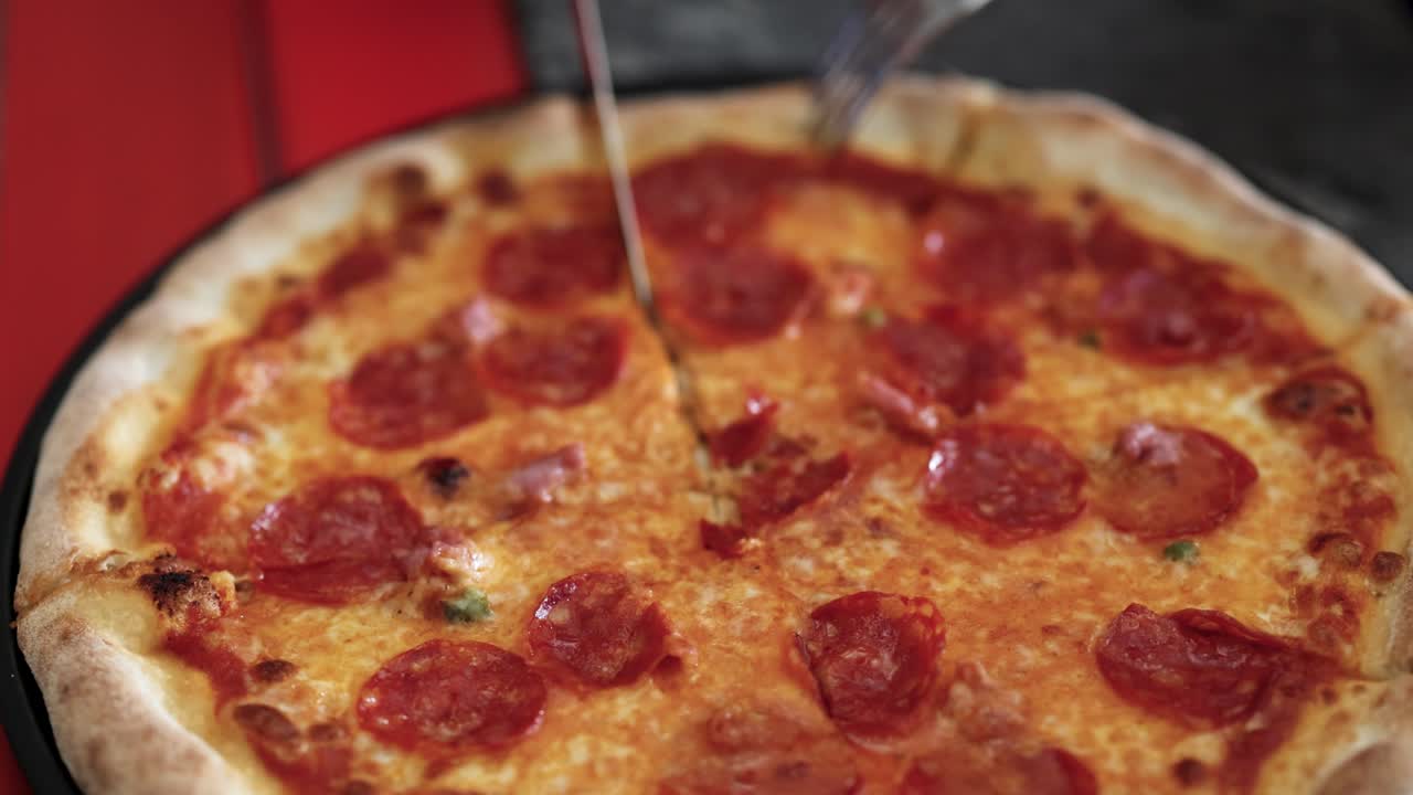 페페로니 피자는 칼로 잘라서 치즈와 토핑을 클로즈업으로 보여줍니다.