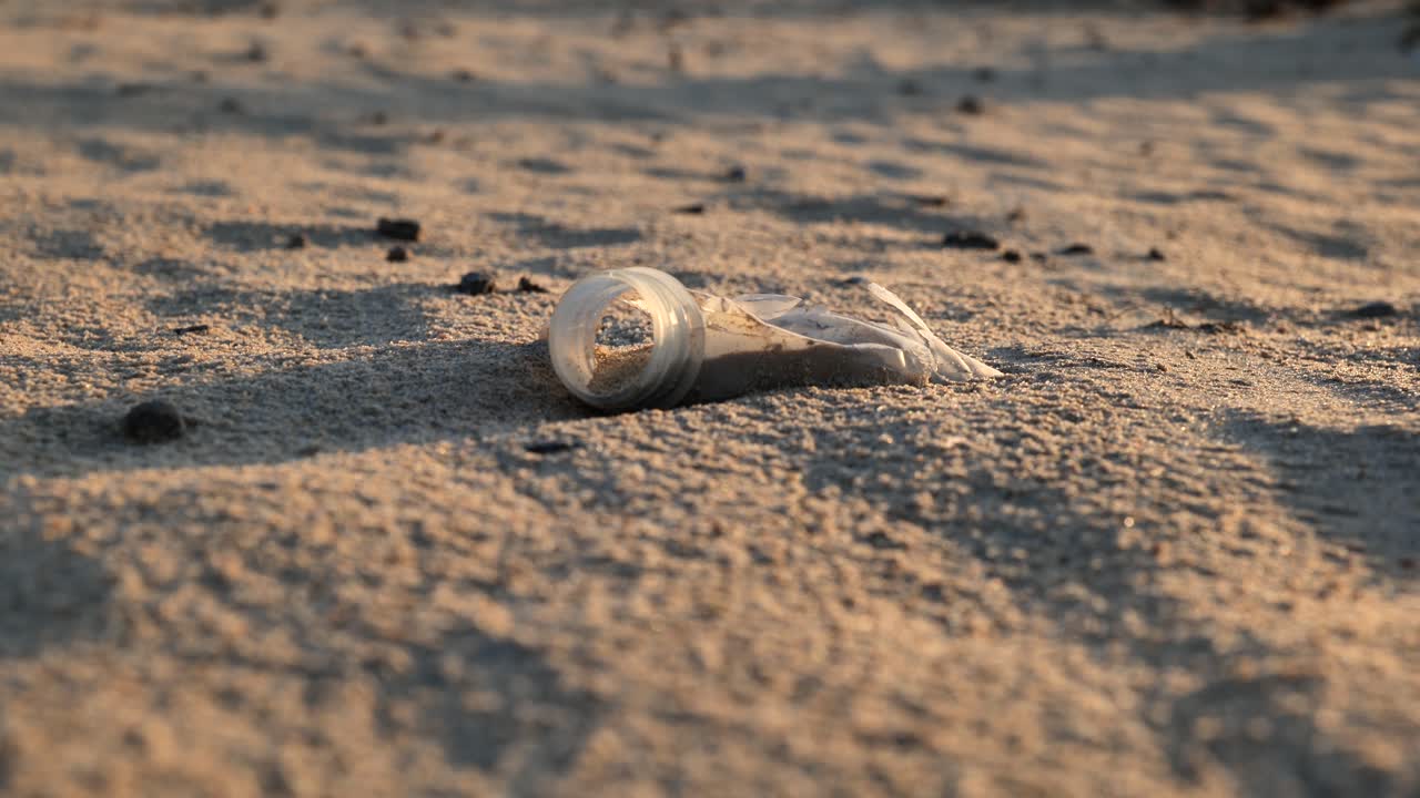 Plastic Bottle Neck on Desert Sand: Environmental Pollution Close-Up