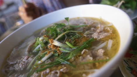 Mujer-En-Bikini-Comiendo-Sopa-De-Fideos-Con-Ternera-Pho-Vietnamita-Tradicional-En-Un-Restaurante-Local