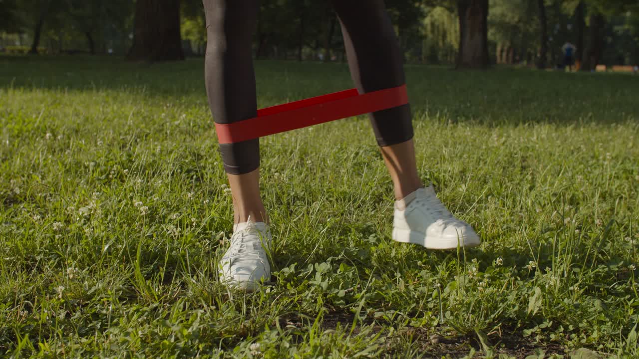 piernas femeninas haciendo ejercicio con banda de resistencia en el parque