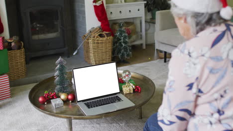 senior caucasian woman in santa hat making laptop christmas video call, copy space on screen