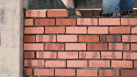 Asian-man-laying-bricks-on-top-of-mortar-to-build-brick-wall