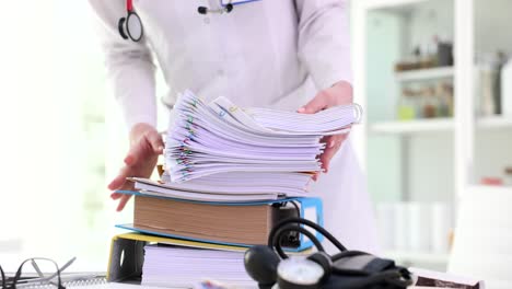 medical professional handling large stack of patient files and paperwork