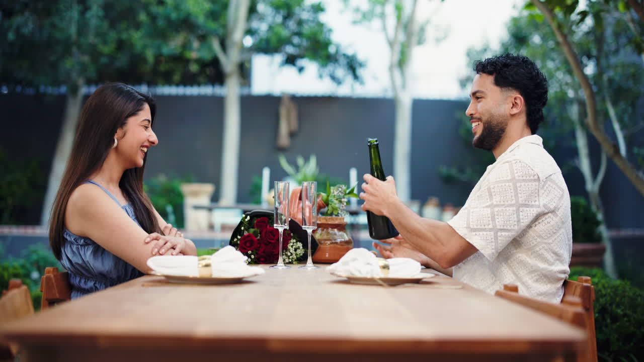 Coppia felice ad un appuntamento romantico all'aperto che versa champagne