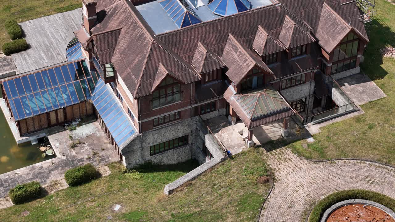 Unfinished celebrity mansion aerial view circling glass rooftop real estate and landscaped gardens