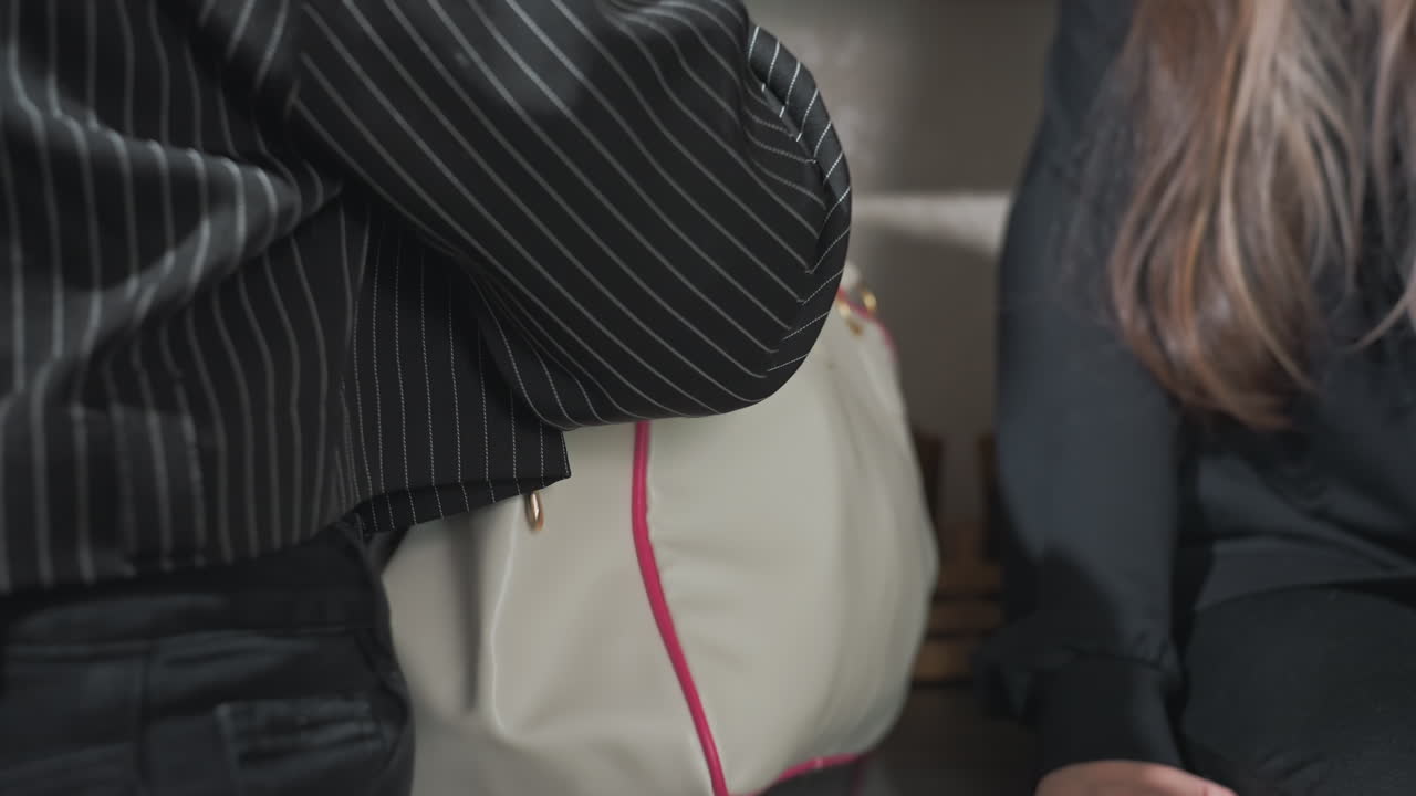 close up of women friends in modern kitchen repacking fresh bread chips and snacks into travel bag after sharing treat exchange while seated on light filled cabinet next to white cupboard