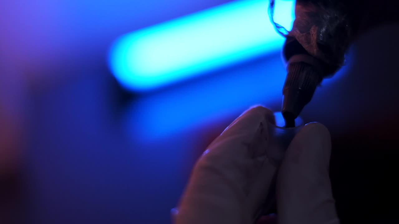 Tatuatore che versa l'inchiostro in una coppetta