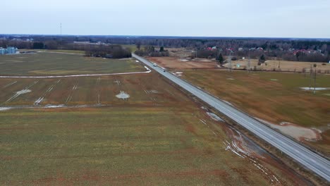 vehicles driving at baltic road between rural fields in the town of pasvalys, lithuania