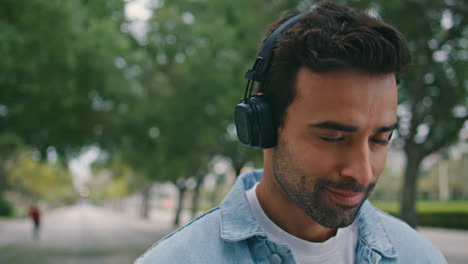 closeup guy listening music in headphones relaxing green park. man in earphones