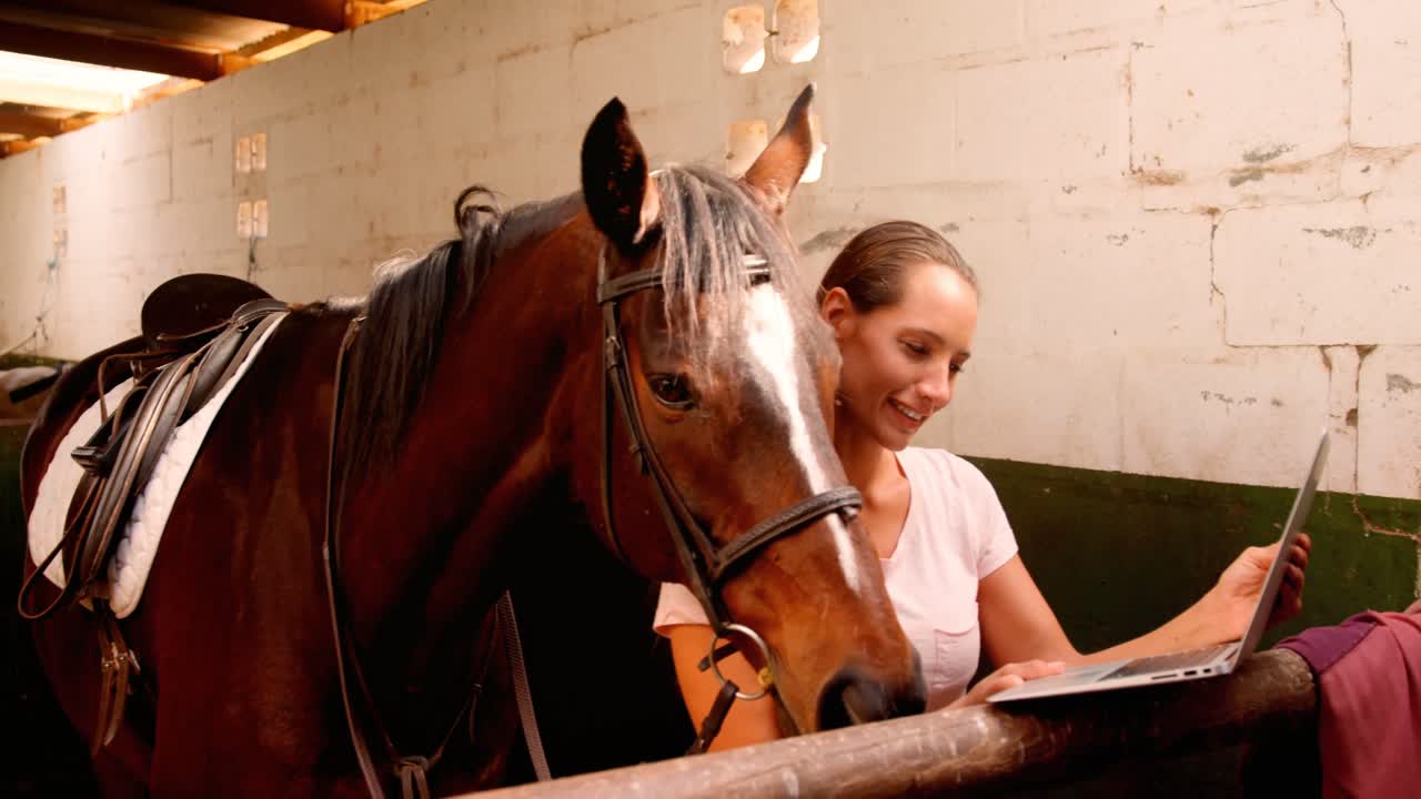 Woman standing with horse using laptop 4k