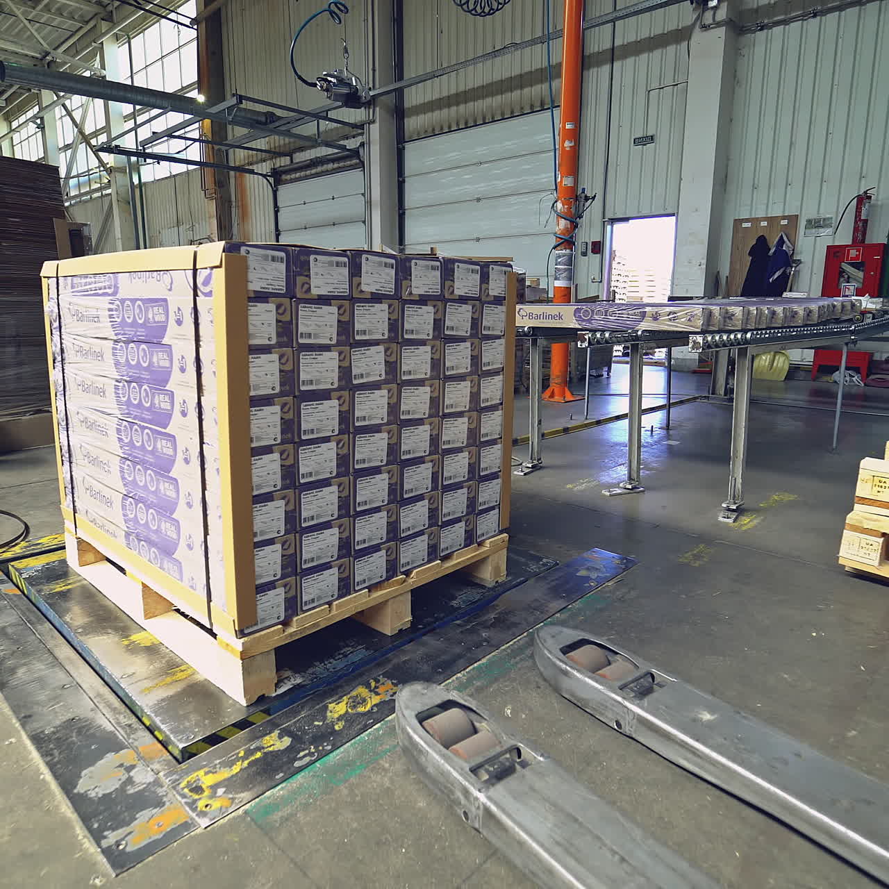 Forklift among the materials in the hangar. Warehousing of wooden slabs