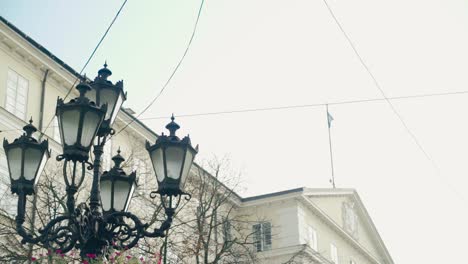 decorative lantern is located in the center of city on the background of urban architecture. camera motion up