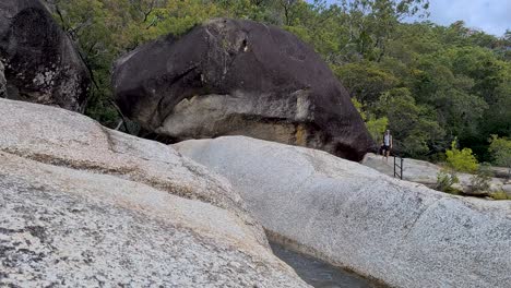 maschio adulto che cammina a piedi nudi e salta con attenzione sul masso a emerald falls creek