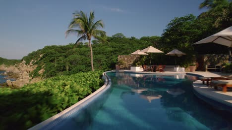 Vista-Aérea-Capturada-Por-Un-Dron-Que-Sobrevuela-Una-Piscina-En-Un-Resort-De-Lujo,-Que-Muestra-El-Estilo-De-Vida-De-Viajes-Y-Vacaciones