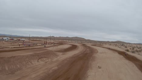 Motorcycles-fly-by-a-first-person-drone-during-a-flight-over-an-off-road-racetrack-in-the-Mojave-Desert