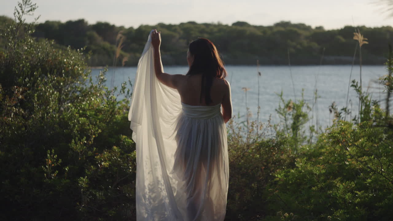 Slow motion shot of a woman in white by a lake at sunset in Albufera Natural Park, Spain.