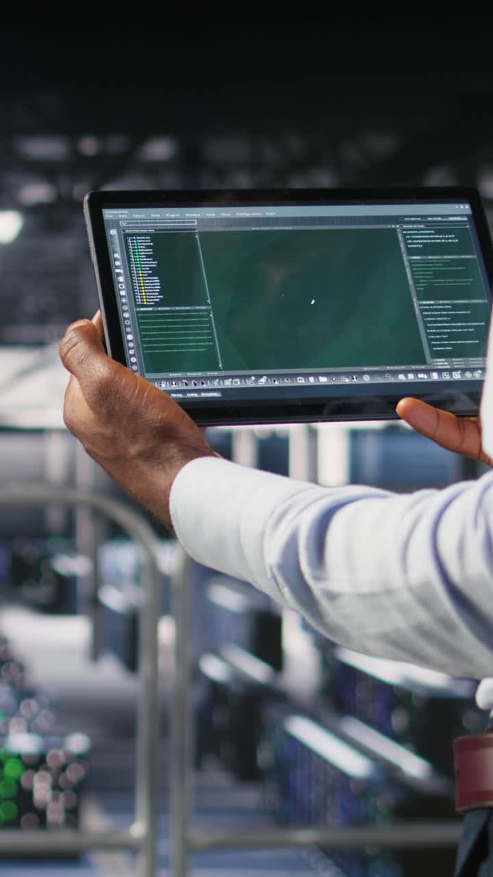 Vertical video Data center admin checking code on tablet next to colleague