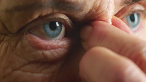 elderly person examining their eye and nose