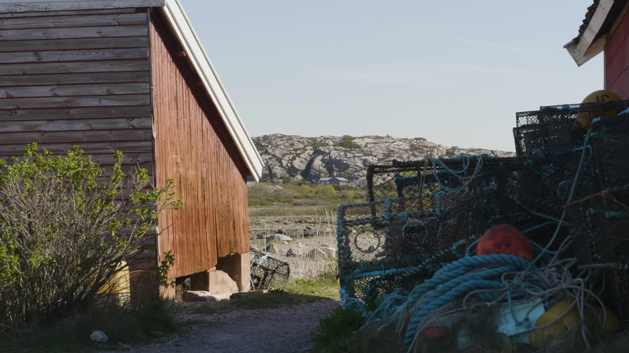 equipo de pesca, ollas de langosta fuera de la cabaña roja del pescador, fondo de paisaje rocoso