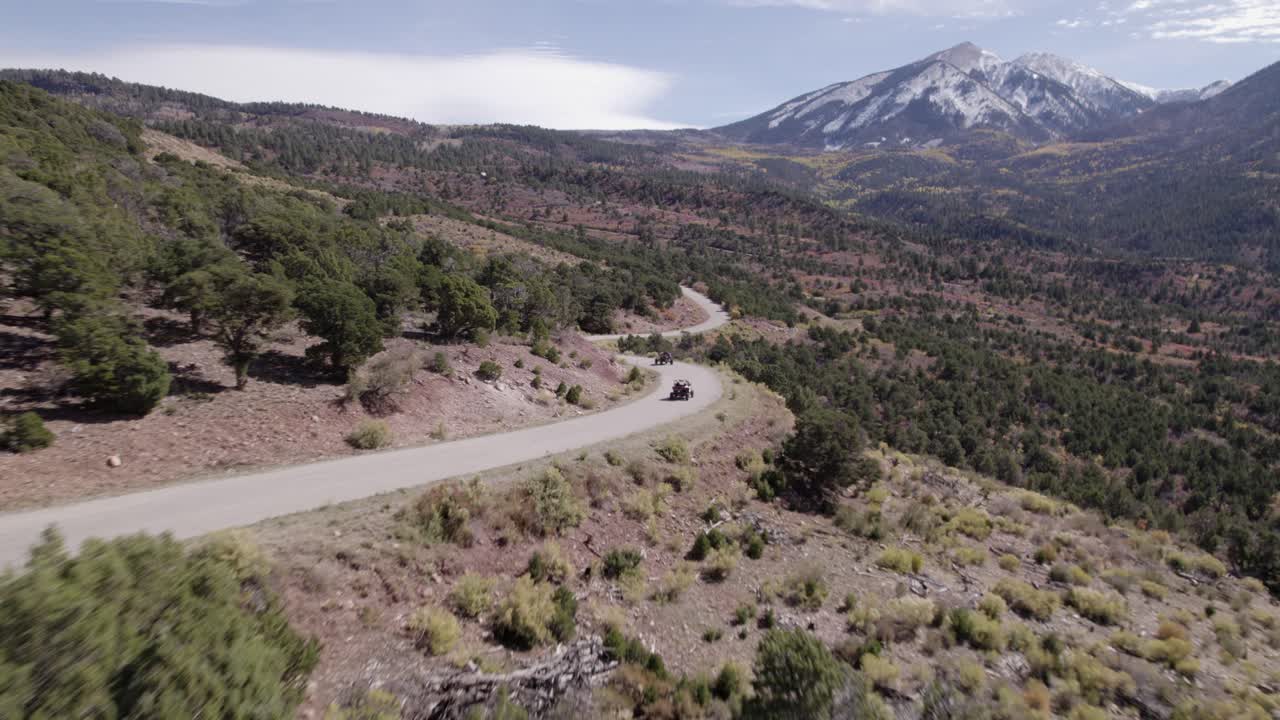 aerial sigue a dos atv que conducen por un camino curvo en el valle del castillo, moab