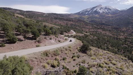 aerial follows two atvs driving on curvy road in castle valley, moab